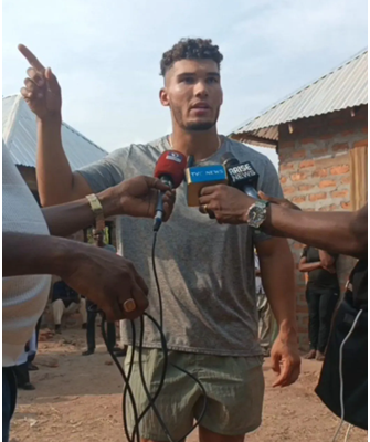 American missionary Alex Barbir standing beside destroyed Yelwata market structures while discussing reconstruction challenges with community survivors in Benue State, Nigeria