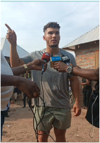 American missionary Alex Barbir standing beside destroyed Yelwata market structures while discussing reconstruction challenges with community survivors in Benue State, Nigeria