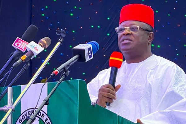 Minister of Works David Umahi speaking at a press briefing in Abuja, with Nigerian government officials seated behind him, as his office issues formal denial of allegations by businesswoman Tracy Nicolas Ohiri regarding police deployment over disputed campaign debt.