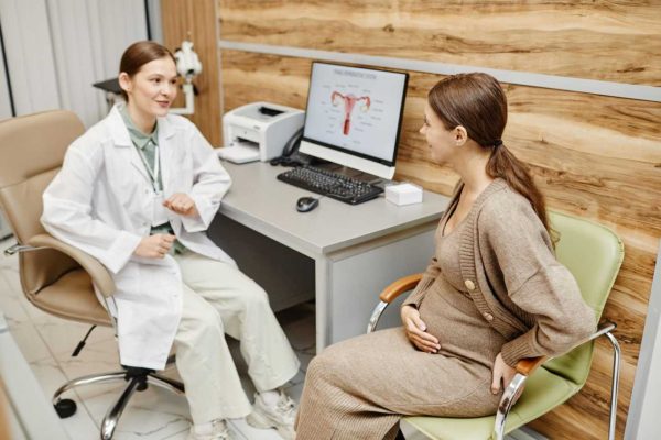 A female doctor consulting with a pregnant woman in a modern clinic about ectopic pregnancy, pelvic pain, emergency symptoms, and reproductive health care.