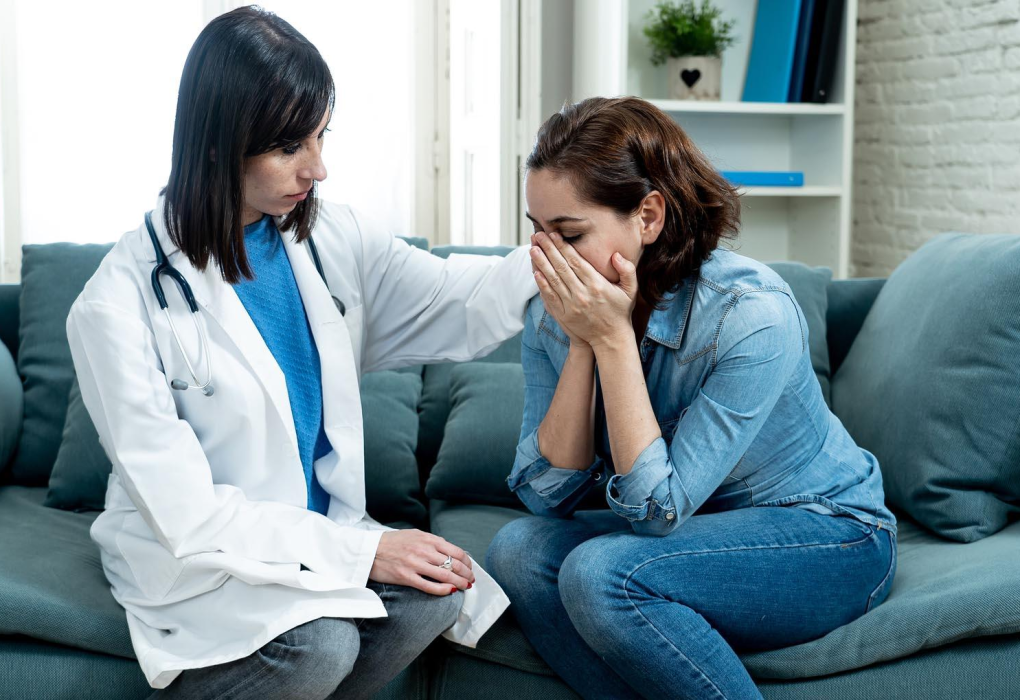 A compassionate female doctor comforting and consulting with a woman in a modern medical clinic about miscarriage, pregnancy loss, recovery, and reproductive health.