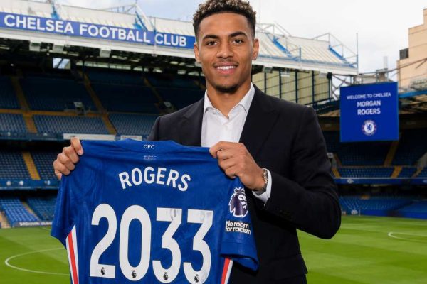 Morgan Rogers holding a Chelsea shirt at Stamford Bridge after completing his transfer from Aston Villa to Chelsea on a long-term contract.